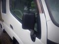 A white 2003 Toyota Toyoace with a black side mirror and water droplets on the surface