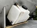 A white plastic tank secured with a strap on a wooden platform attached to a vehicle