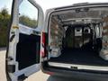 A 2023 Ford Transit van with the rear doors open revealing a spacious empty cargo area with wooden shelving and a black partition wall