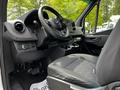 Interior view of a 2023 Mercedes-Benz Sprinter featuring a steering wheel dashboard and driver's seat with fabric upholstery and control buttons