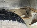 A close-up of the undercarriage of a 2006 Ford Econoline showing a metal frame and a tire with a textured tread pattern