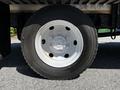 Close-up of a tire from a 2013 Mitsubishi Fuso FE160 featuring a silver wheel rim and a black tread with visible markings on the sidewall