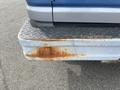 Close-up of the rear corner bumper of a 2009 Ford Econoline showing significant rust and wear on the metal surface
