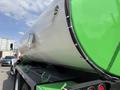 A 1996 Kenworth T800 truck with a prominent silver tank painted green on the top and secured with metal fasteners