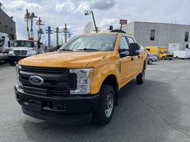 A 2017 Ford F-250 Super Duty pickup truck in bright yellow with a black grille and front bumper parked with its front angled towards the viewer