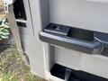 A close-up of a door panel in a 2016 Ford F-150 featuring a black door handle and a control button