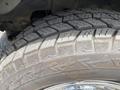 Close-up of a rugged tire with deep treads mounted on a wheel part of a 2023 GMC Savana