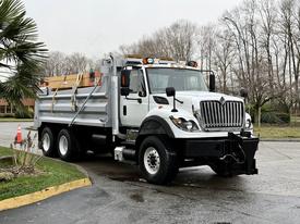 A white 2012 International WorkStar dump truck with a black front grille and chrome accents is parked with the dump bed raised slightly