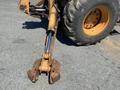 A 2008 Case Super 580M backhoe loader with a large metal bucket attachment and a hydraulic boom arm in a rusted condition