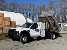 A 2008 Ford F-450 SD truck with a dump bed raised, showcasing its utility design and strong build