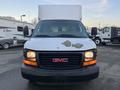 A 2009 GMC Savana with a white paint job and a prominent GMC logo on the front grille showing signs of wear and fading