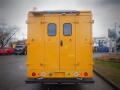 A yellow 2008 Freightliner MT45 Chassis viewed from the rear with two windows and a light on top