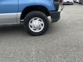 A blue and silver 2010 Ford Econoline van with a visible front tire on a gray surface