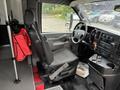 Interior of a 2020 Chevrolet Express showing the driver's seat, steering wheel, dashboard with controls, and a red jacket hanging on the passenger seat