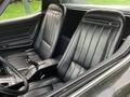 Interior of a 1972 Chevrolet Corvette featuring two black leather bucket seats with vertical stitching and a center console.