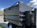 A 2016 Isuzu NPR with a black dump truck bed featuring a side ladder and a hydraulically operated dump mechanism