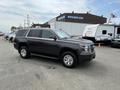 A 2016 Chevrolet Tahoe parked with a shiny dark exterior and silver wheels showcasing its sturdy SUV design