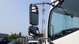 A white 2013 Hino 268 truck with a large side mirror reflecting the surroundings and a second smaller mirror attached to the same arm