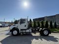 A 2003 Freightliner M2 106 truck with a white cab and chassis is parked with no cargo in the foreground