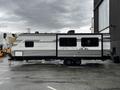 A 2022 Aspen Trail travel trailer featuring a silver and black exterior with a distinctive design and two axles