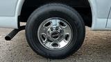 Close-up of a chrome wheel rim with a tire mounted on a 2005 Chevrolet Express showing details of the tire tread and the shiny metal hubcap