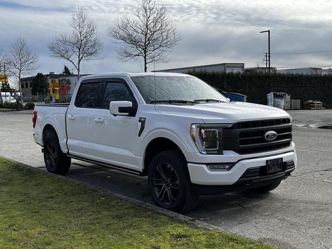 A white 2021 Ford F-150 parked on a pavement with a four-door extended cab and black wheels