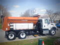 A 2016 International WorkStar 7500 truck with a large orange dump body and black chassis designed for transporting materials and equipment