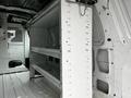 Interior of a 2009 Ford Econoline with white metal shelving and a metal divider partition