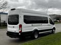 A white 2021 Ford Transit van with a black lower trim parked on a street mainly showing its rear and side profile