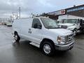 A white 2014 Ford Econoline van with a ladder rack on the roof and side doors visible