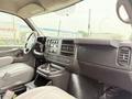 Interior of a 2014 GMC Savana featuring a driver’s dashboard with controls and a center console with cup holders and storage compartments