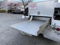 A 2008 Ford F-450 with a metal flatbed and a drawer partially extended from the back containing hoses and tools