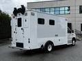 A 2013 Ford Econoline van with a white exterior featuring side windows and a rear door setup designed for utility or service purposes