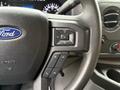 Close-up of a 2022 Ford E-450 steering wheel featuring controls for volume and media functions