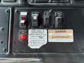 Control panel of a 2010 Autocar Xpeditor featuring buttons for hydraulic pump and work lights along with warning indicators and a notice about hydraulic fluid level