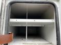 Interior of a 2013 Ford Econoline showing empty storage space with white shelves and a metallic frame