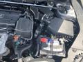 The engine compartment of a 2017 Acura TLX showing the engine, battery, and various components with wires and hoses connected