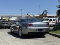 A silver 2005 Ferrari 612 Scaglietti parked with sleek lines and a sporty design showcasing its rear and dual exhausts
