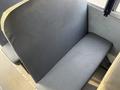 A grey upholstered seat in a vehicle interior designed for passenger transport with a flat backrest and a simple, functional design