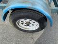 A close-up of a blue U-Built Reel Trailer tire showing a silver wheel rim with multiple holes and a worn black tire with visible tread patterns