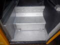 A set of silver diamond plate steps inside a yellow 2008 Freightliner MT45 chassis with a storage compartment underneath