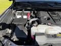 Close-up of the engine compartment of a 2023 Toyota Tundra showcasing various components such as the battery coolant reservoir and engine cover
