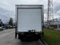 A 2018 Isuzu NRR box truck with a white rear cargo door parked on the street