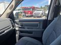 A gray interior view of a 2015 RAM 1500 featuring the driver’s side door with controls and a textured seat