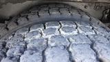 A close-up view of a worn tire with deep treads on a 2014 Freightliner Thomas Bus Diesel showing signs of significant use