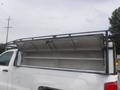 White 2015 Chevrolet Silverado 1500 with an open utility cover revealing storage shelves inside