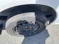 A flat tire on a 2019 Nissan NV200 showing a black steel wheel and worn tire tread