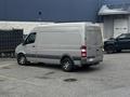 A 2010 Mercedes-Benz Sprinter van parked with a silver exterior and tinted windows featuring a high roof and large cargo area