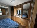 Interior view of a 2000 Ford Motorhome featuring a bed with a blue mattress and wooden cabinetry including a mirrored closet and built-in storage