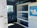 Interior of a 2006 Ford Econoline van showing empty shelves mounted on the walls and a blue interior with minimal furnishings